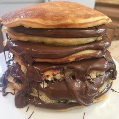 a stack of chocolate covered pancakes sitting on top of a white plate