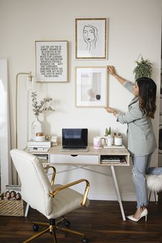 a woman standing in front of a desk with a laptop on it