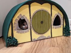 a cat is peeking out from the inside of a house shaped like a fairy tale