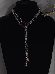 This stunning women's necklace features a unique snowflake obsidian stone with a pear-shaped crystal quartz drop and  garnet accents. The two-strand necklace is 23 inches in length with a toggle closure for easy wear. The intricate beading and layered design make it a perfect statement piece for any occasion. The necklace is made of high-quality materials including crystal quartz, garnet,  and has an adjustable length for a comfortable fit. It draws inspiration from nature, making it an ideal accessory for vacation, beach, bohemian, or retro outfits. Whether you want to add a touch of class, love, or fantasy to your outfit, this necklace is the perfect choice. Elegant Adjustable Teardrop Pendant Crystal Necklace, Elegant Adjustable Crystal Teardrop Pendant Necklace, Elegant Adjustable Teardrop Crystal Necklace, Adjustable Crystal Lariat Necklaces, Art Nouveau Necklaces, Intricate Beading, Inspiration From Nature, Women's Necklace, Obsidian Stone