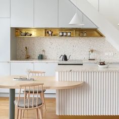 an open kitchen with white cabinets and wooden flooring, along with a round dining table surrounded by chairs