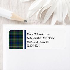 a white envelope with a black and green plaid address stamp on it next to a pencil