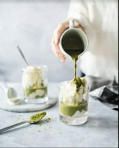 someone pouring green tea into small glasses with ice cream and matchsticks on the side