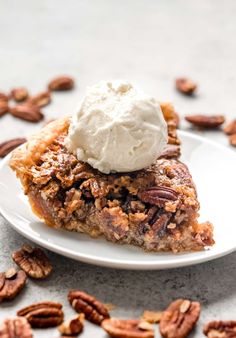 a slice of pecan pie on a plate with whipped cream and pecans around it