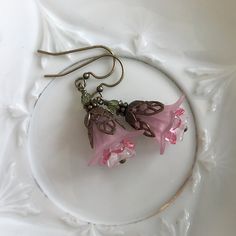 "Pretty in Pink... Add some spring to your wardrobe with these lovely double pink blossoms. Delicate pink petals surround bright pink and white centers. Antique brass filigree caps adorn the tops and a tiny green bead adds a bit of spring pop. These earrings are very lightweight and comfortable to wear. Perfect for a garden wedding, or a gift for a nature lover. And don't forget...Mother's Day is just around the corner. Drop length from bottom of antique brass french earwire: 1\" (25mm) Prefer a Pink Earrings With Handmade Flowers For Spring, Pink Handmade Flower Earrings For Spring, Pink Petal-shaped Earrings For Spring, Spring Pink Earrings With Flower Charm, Spring Pink Earrings With Handmade Flowers, Pink Feminine Dangle Flower Earrings, Pink Feminine Flower Dangle Earrings, Feminine Pink Dangle Flower Earrings, Delicate Pink Flower Jewelry