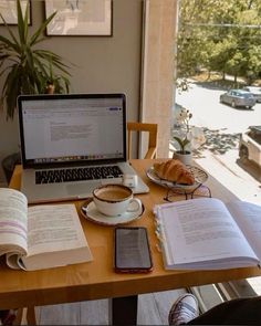 a laptop computer sitting on top of a desk next to an open book and cup of coffee