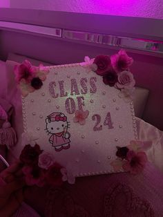 a hello kitty pillow that says class of 24 with pink flowers on the front and bottom