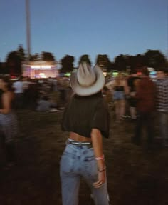 a person with a cowboy hat standing in front of a group of people at night