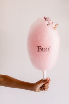 a person holding a pink lollipop with the word boof written on it