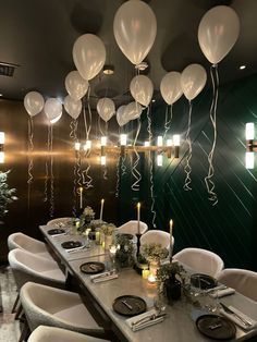 a long table with white balloons hanging from the ceiling