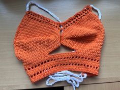 an orange crocheted bow tie on top of a wooden table