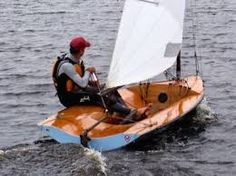 a man riding on the back of a small sailboat in the middle of water