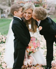 a couple of kids that are standing next to each other in front of some flowers