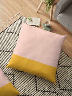 two pillows sitting on top of a rug next to a chair and coffee mugs