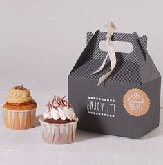 two cupcakes are sitting next to an empty box