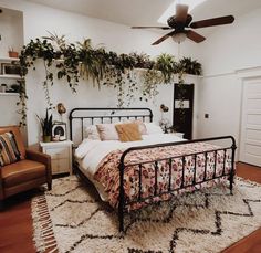 a bed room with a neatly made bed next to a chair and a ceiling fan