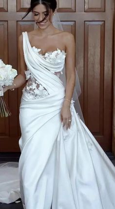 a woman in a white wedding dress holding flowers