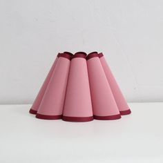 pink cone shaped lampshade on white surface with red trim around the top and bottom