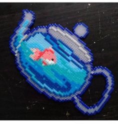 a blue teapot with a goldfish in it on a black table next to other items