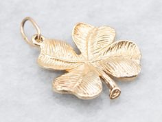 a gold four leaf clover charm on a white background