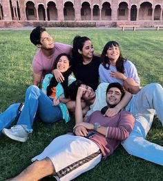 a group of people sitting on top of a grass covered field next to each other