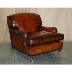 a brown leather chair sitting on top of a cement floor