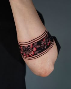 a woman's arm with a tattoo on it and flowers in the band around her wrist