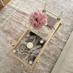 a table with pink roses and candles on it in front of a white bed sheet