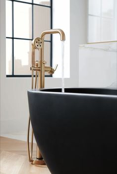 a black bath tub sitting on top of a wooden floor