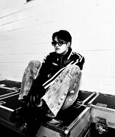 a young man sitting on top of an old suitcase