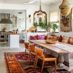 a dining room table with chairs and rugs on the floor in front of it