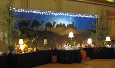 a christmas scene is displayed on the wall behind a table with lamps and decorations in front of it