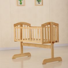 a wooden baby crib sitting on top of a hard wood floor next to two framed pictures