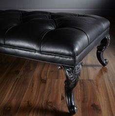 a black leather bench sitting on top of a wooden floor