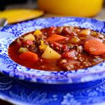 a blue and white bowl filled with stew on top of a table next to yellow dishes