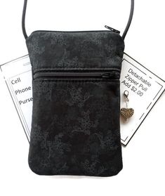 a small black purse sitting on top of a pile of cards next to a cell phone