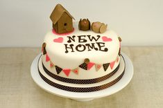 there is a cake that says new home on the top and two small birds sitting on it