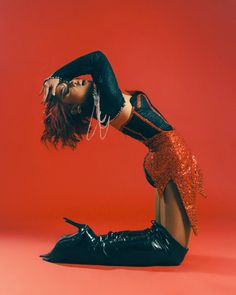 a woman in black and red is posing on the floor with her legs spread out