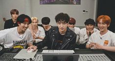 group of young men sitting in front of a computer keyboard and monitor with one person on it