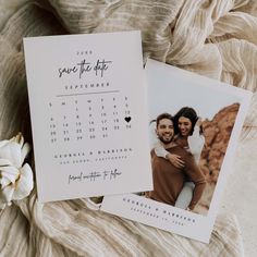 two wedding save the dates cards on top of each other with a flower in front of them