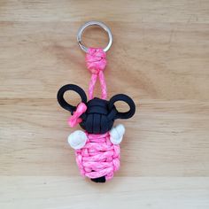 a pink and black keychain shaped like a sheep on a wooden surface with a metal hook