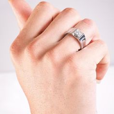 a person's hand with a diamond ring on their finger and the thumb up