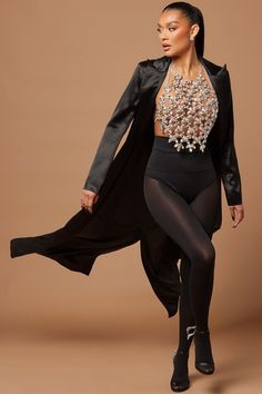 a woman in tights and heels is posing with a jacket over her shoulders,