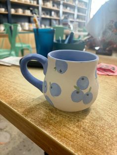 a blue and white coffee cup sitting on top of a wooden table in a shop