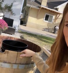 a woman is holding a bucket in front of a barrel with pink flowers on it