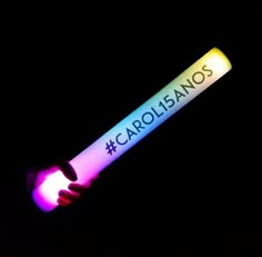 a person holding a lit up tube with the word carolinas written on it at night