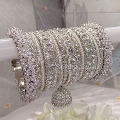 a bunch of bracelets that are on top of a white chair with flowers in the background