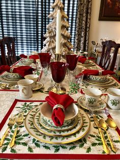 the table is set for christmas dinner with red napkins and gold placemats