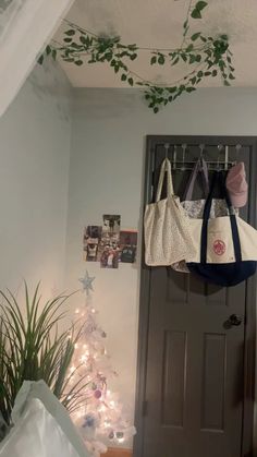 two purses hanging from hooks in front of a door with christmas decorations on it