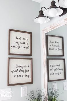 a bathroom sink sitting under a mirror next to two framed pictures and a potted plant